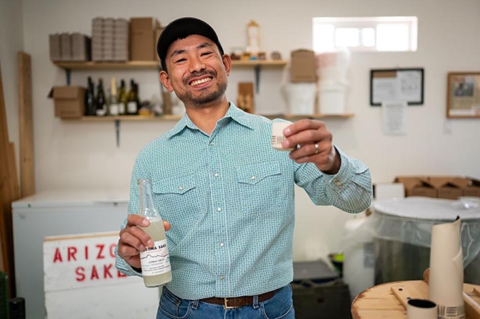 Atsuo Sakuri the founder of the Arizona Sake Shop holding a glass bottle of sake