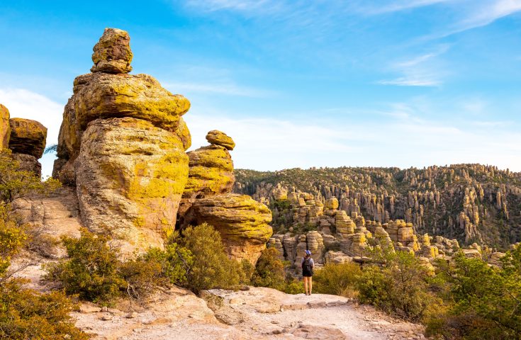 Woman stands next to a hoodoo in Chiricahua National Monument in Willcox